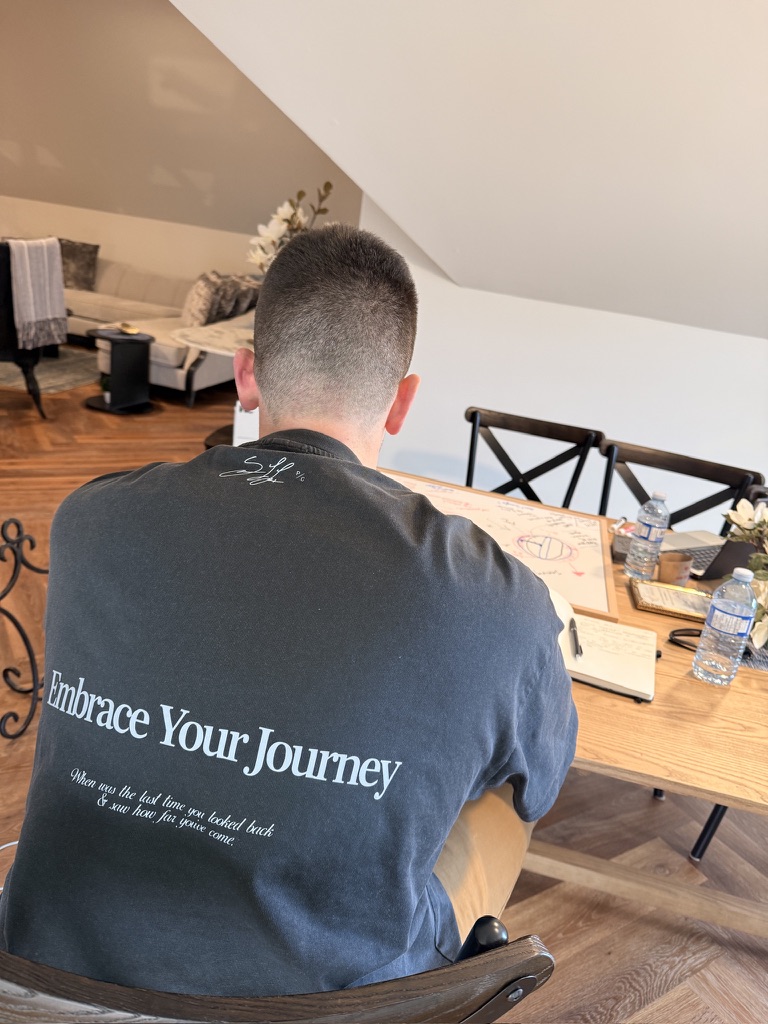 Ken King at his desk, shirt reading Embrace Your Journey